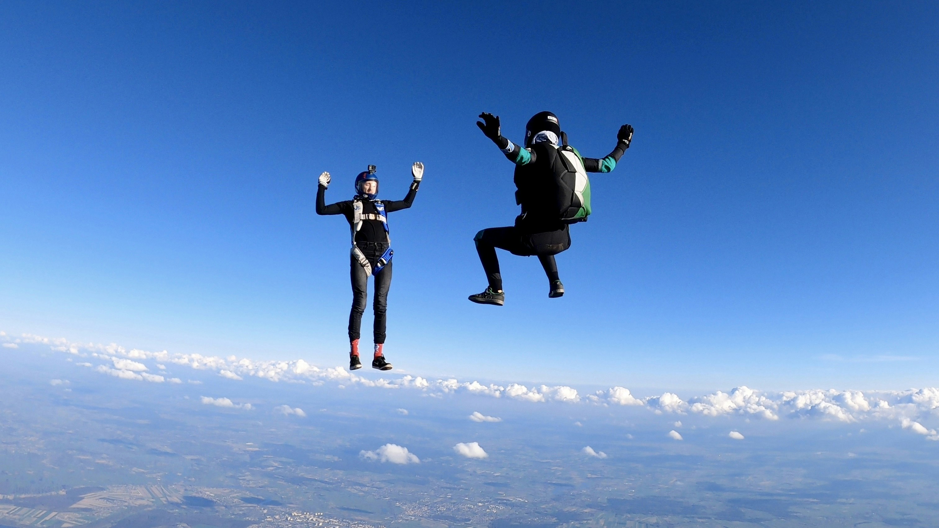 2 women in black jacket and pants jumping on white clouds during