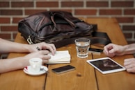 Black-and-white shot of a client meeting with notes and coffee on the table.