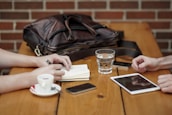 A casual meeting around a wooden table with laptops, coffee cups, and brainstorming notes.