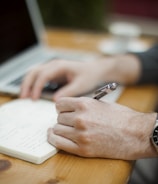 A person writing content in a stylish notebook.
