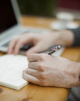 A relaxed learner taking notes while watching a history lecture on a smartphone.