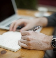 A calm setting with a person writing a budget plan in a notebook.