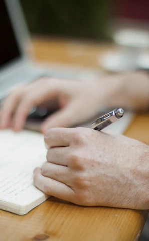 A relaxed learner taking notes while watching a history lecture on a smartphone.