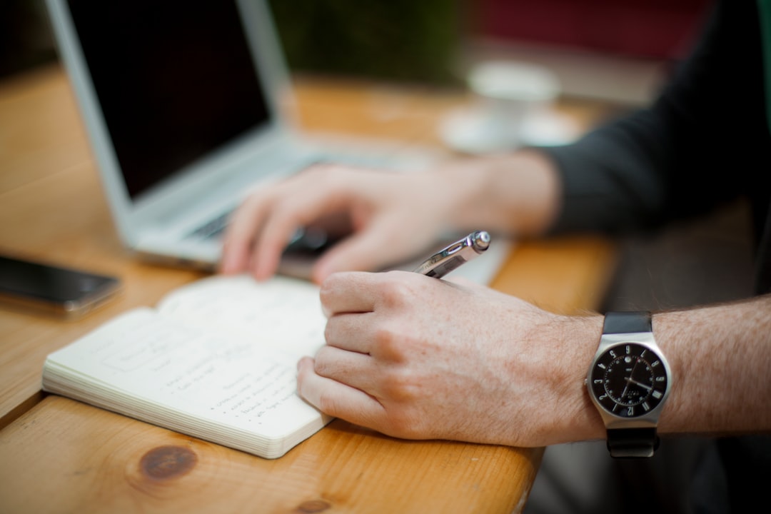 man sitting while writing on notebook man sitting while writing on notebook