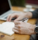 man sitting while writing on notebook