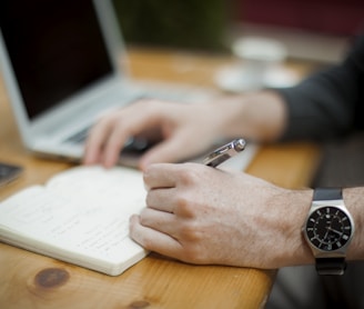 man sitting while writing on notebook