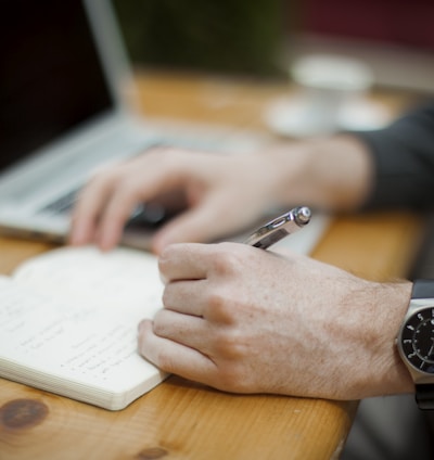 man sitting while writing on notebook