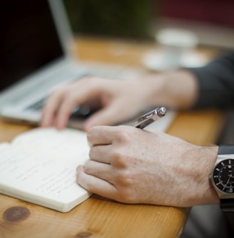 man sitting while writing on notebook