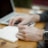 man sitting while writing on notebook