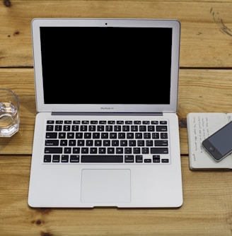 MacBook Air beside black iPhone 4 and drinking glass