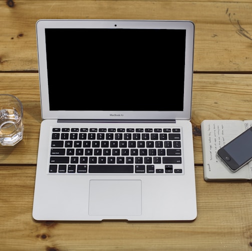 MacBook Air beside black iPhone 4 and drinking glass