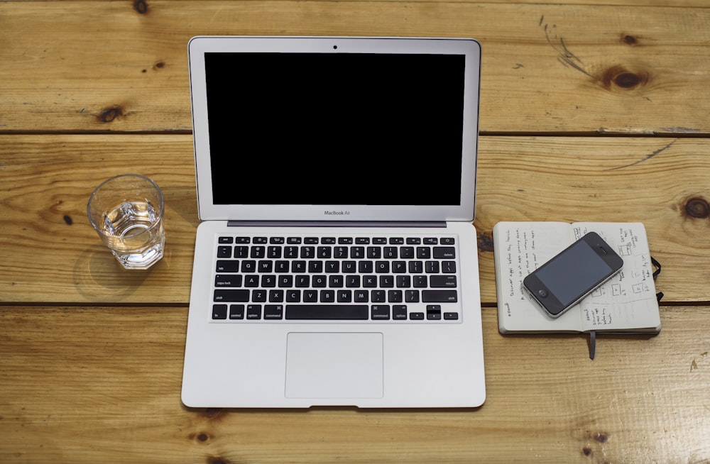 MacBook Air beside black iPhone 4 and drinking glass