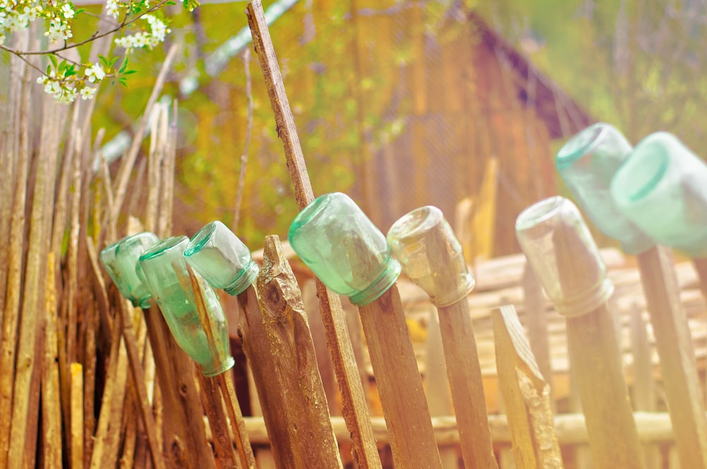 green glass jars on brown wooden fence