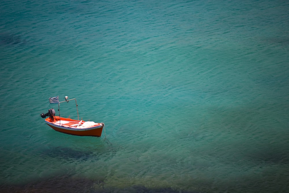 barca rossa sull'oceano blu durante il giorno