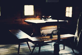 A warmly lit wooden table strewn with ancient scrolls, quills, and a glowing candle, set within a cozy medieval tavern corner.