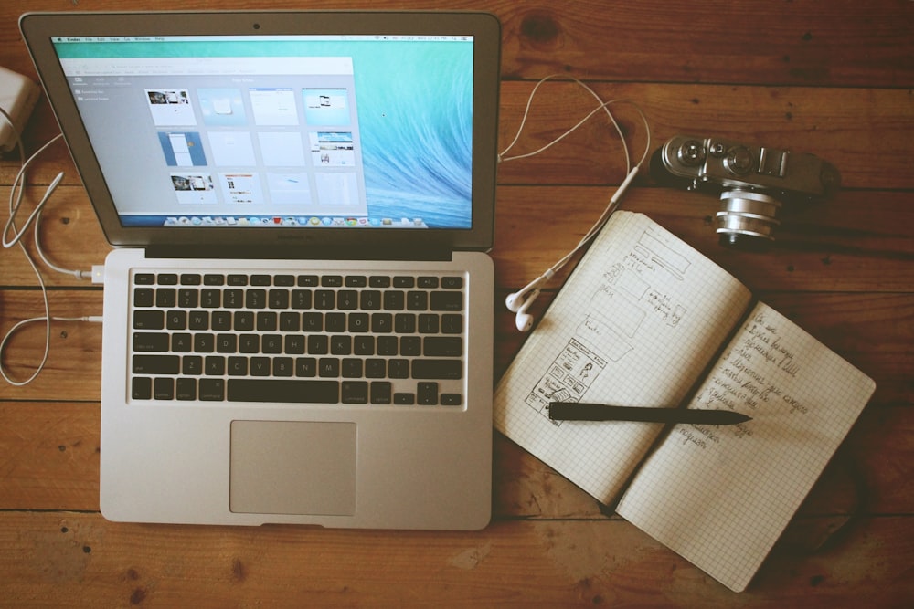 switched on MacBook Air beside a handwritten note on a writing notebook.