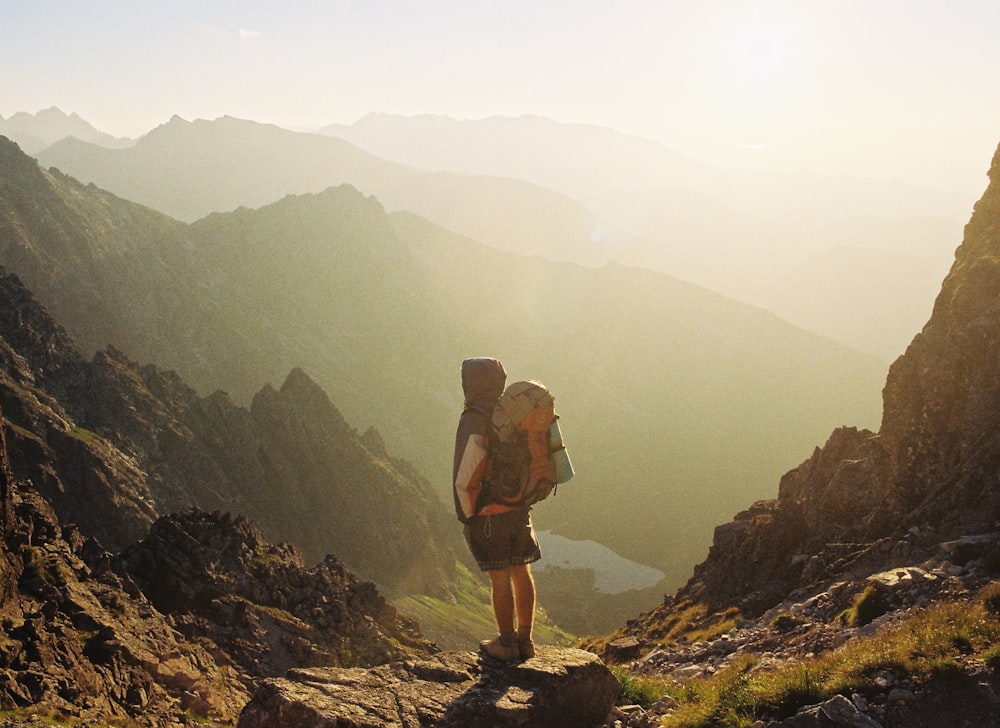 climber standing on rock near overlooking view of mountain at daytime