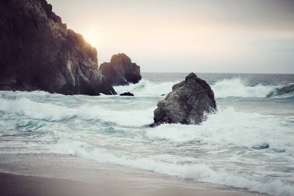 photography of rock formation on body of water