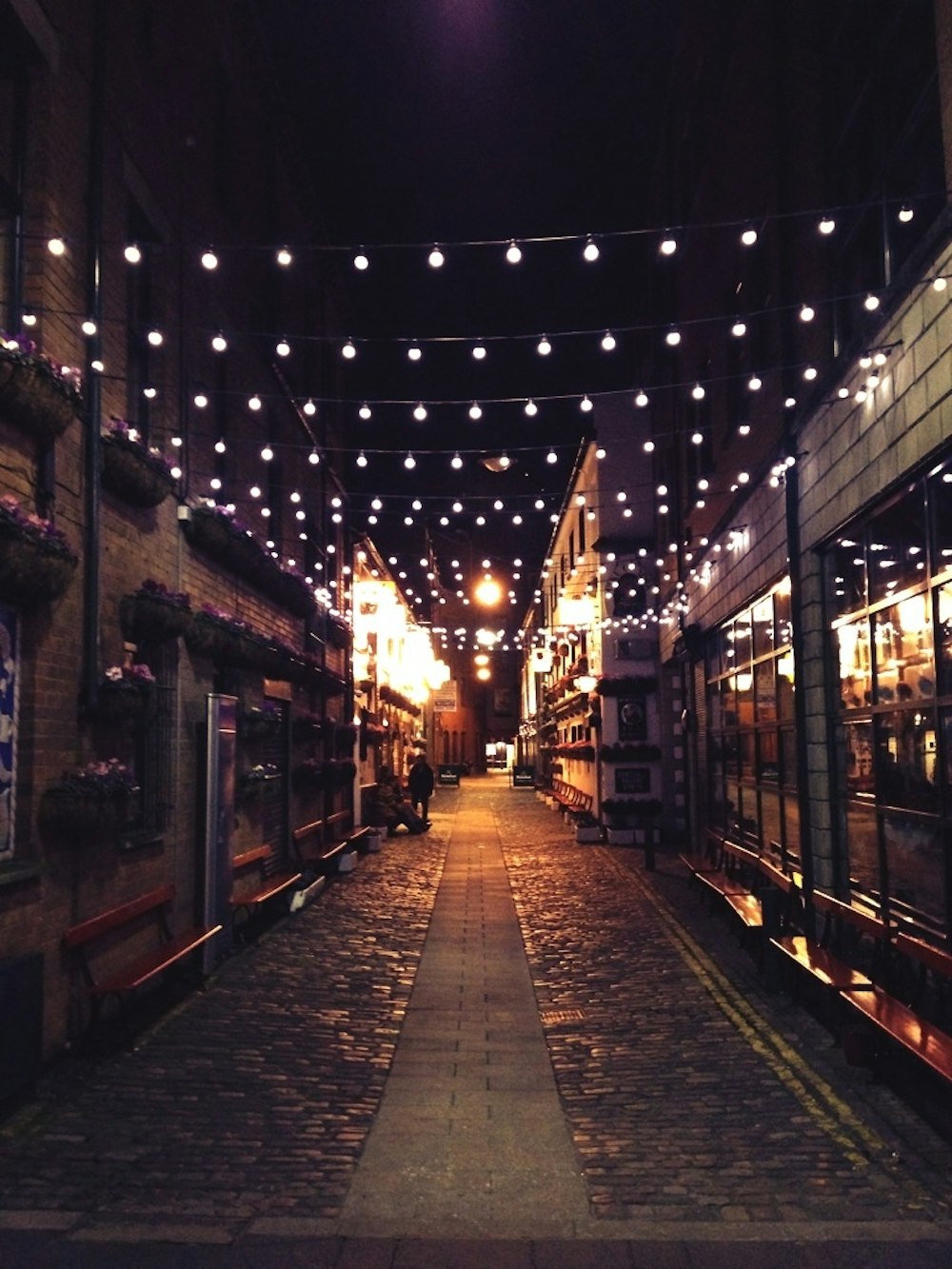Foto de una calle estrecha con bombillas durante la noche