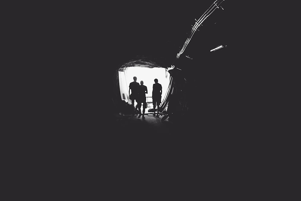 three person standing in tunnel