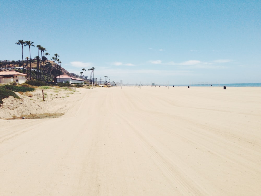 Praia de areia branca sob o céu azul claro durante o dia