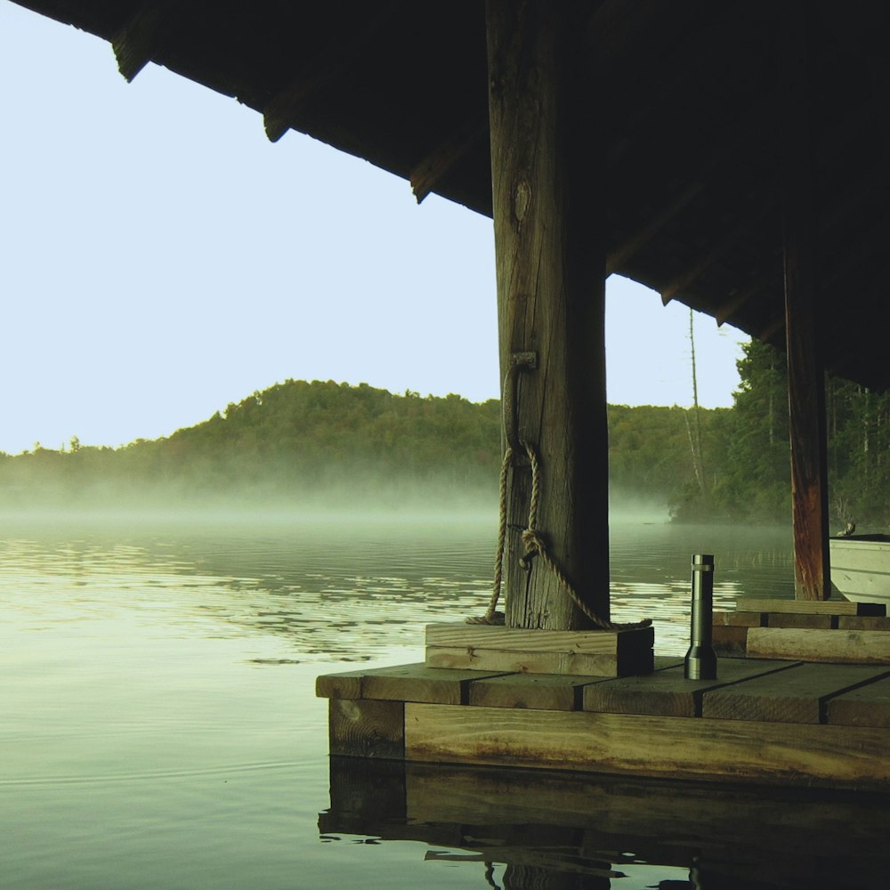 silver flashlight on wooden surface near body of water