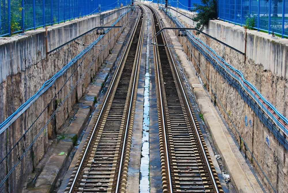 日中の茶色のコンクリートの壁の間の茶色の電車のレールの写真