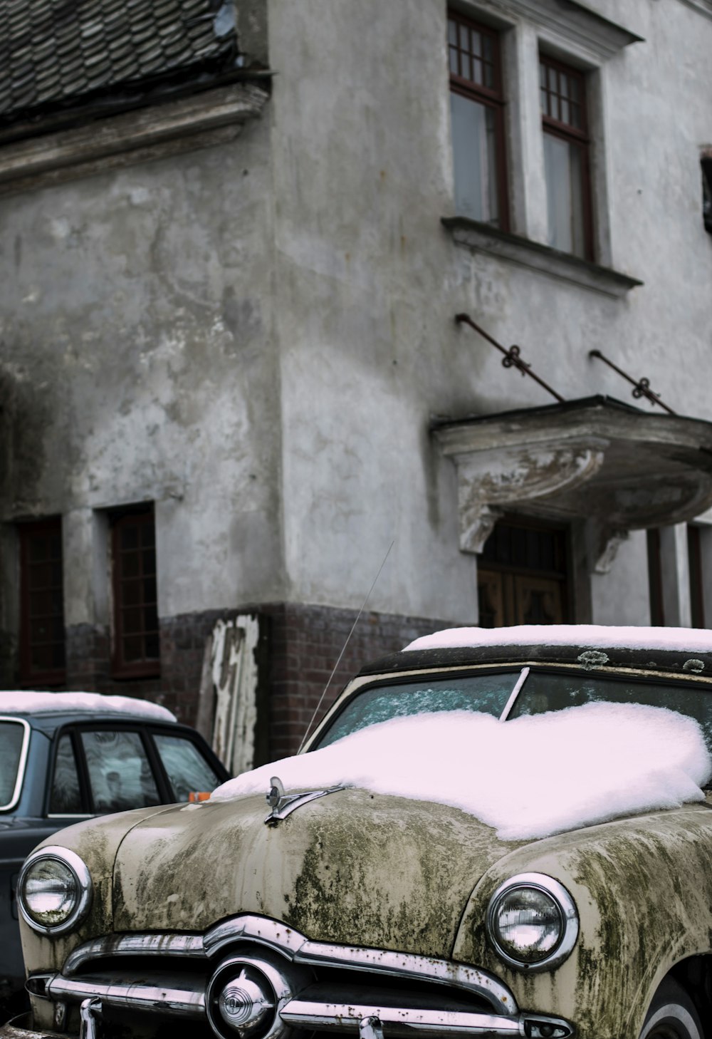 brown vehicle covered with snow park beside gray concrete building