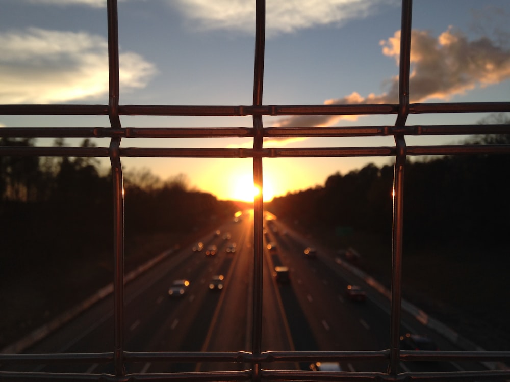 vehicles on highway between silhouette of trees