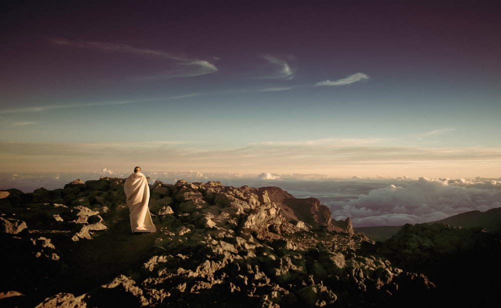 pessoa vestindo manto branco no topo da montanha rochosa
