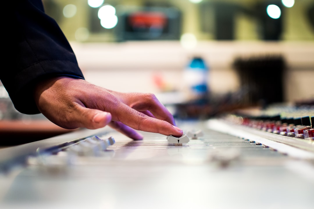 A close-up of a person's hand adjusting a dial on a music mixer