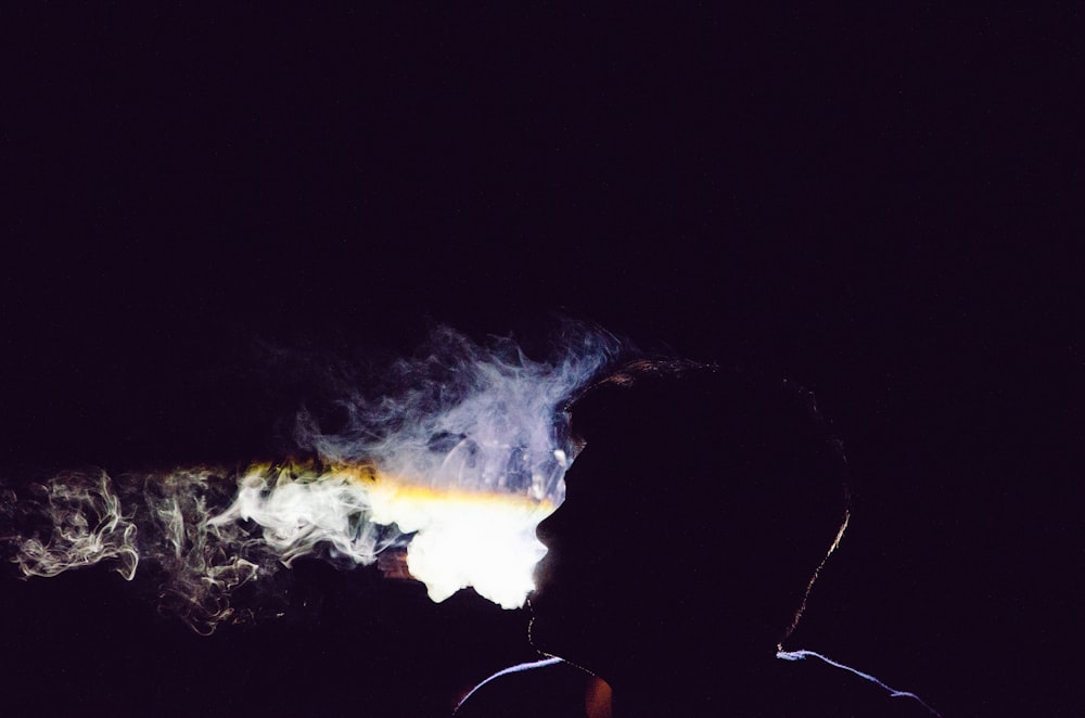 a man standing in the dark with smoke coming out of his face