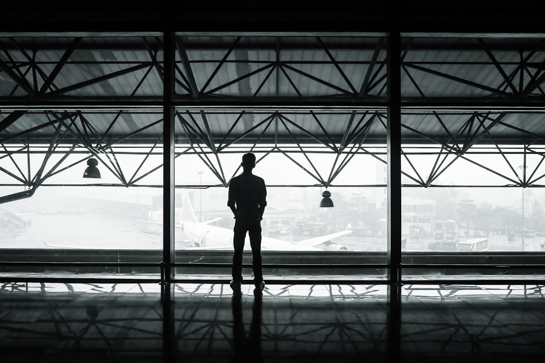 silhouette of man standing between two posts, Man looks out airport window