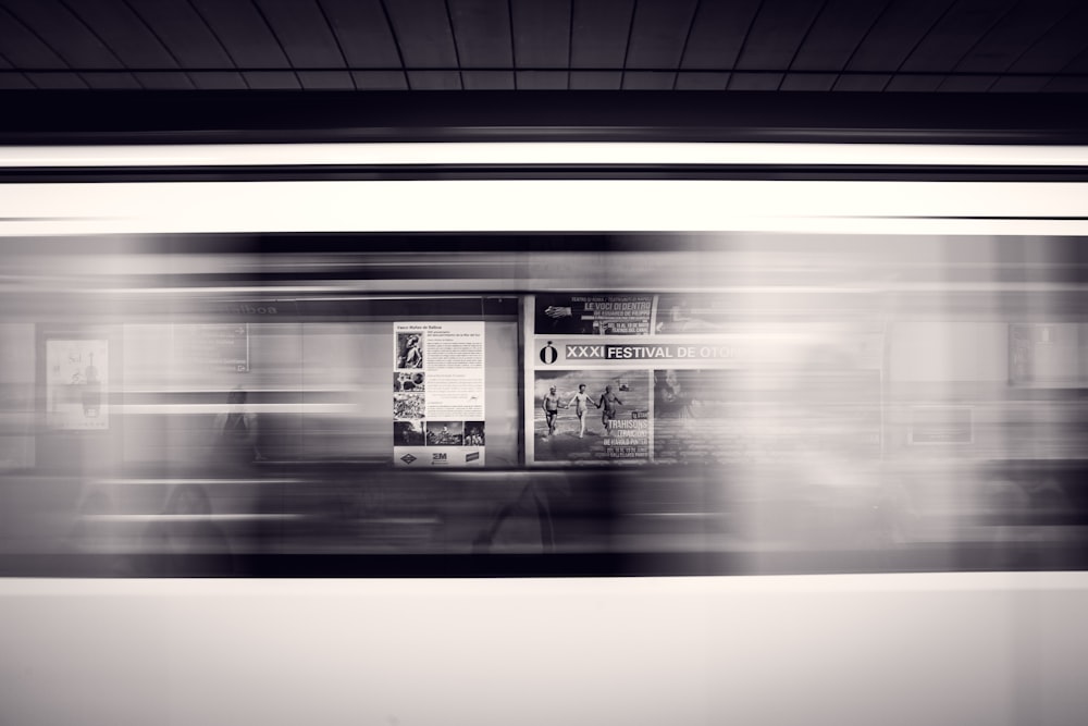 A long-exposure shot of a moving subway train and advertisement posters at the station