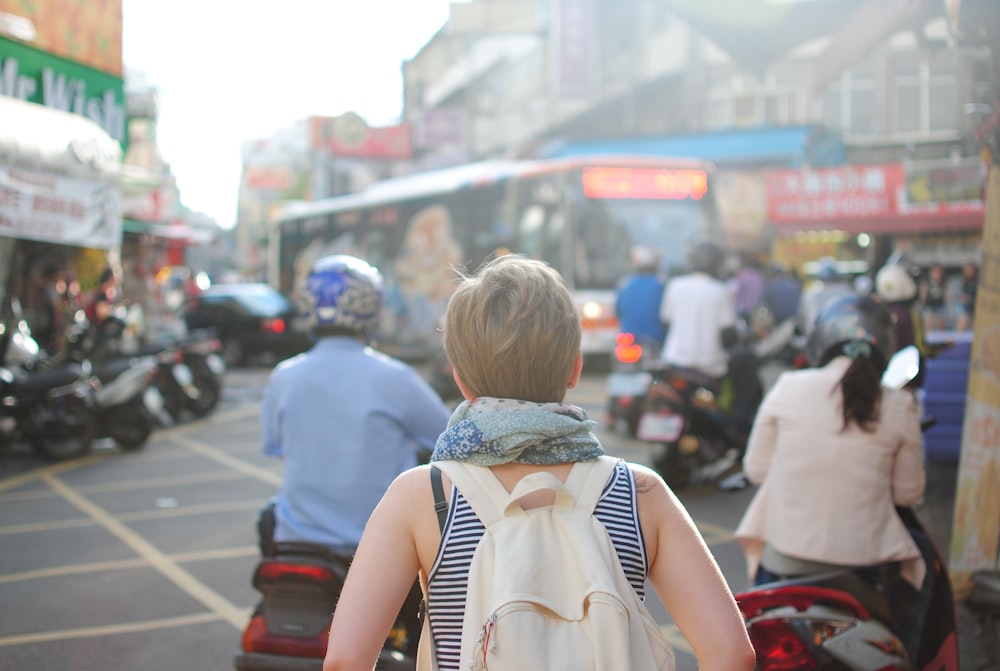 woman wearing backpack walking on road