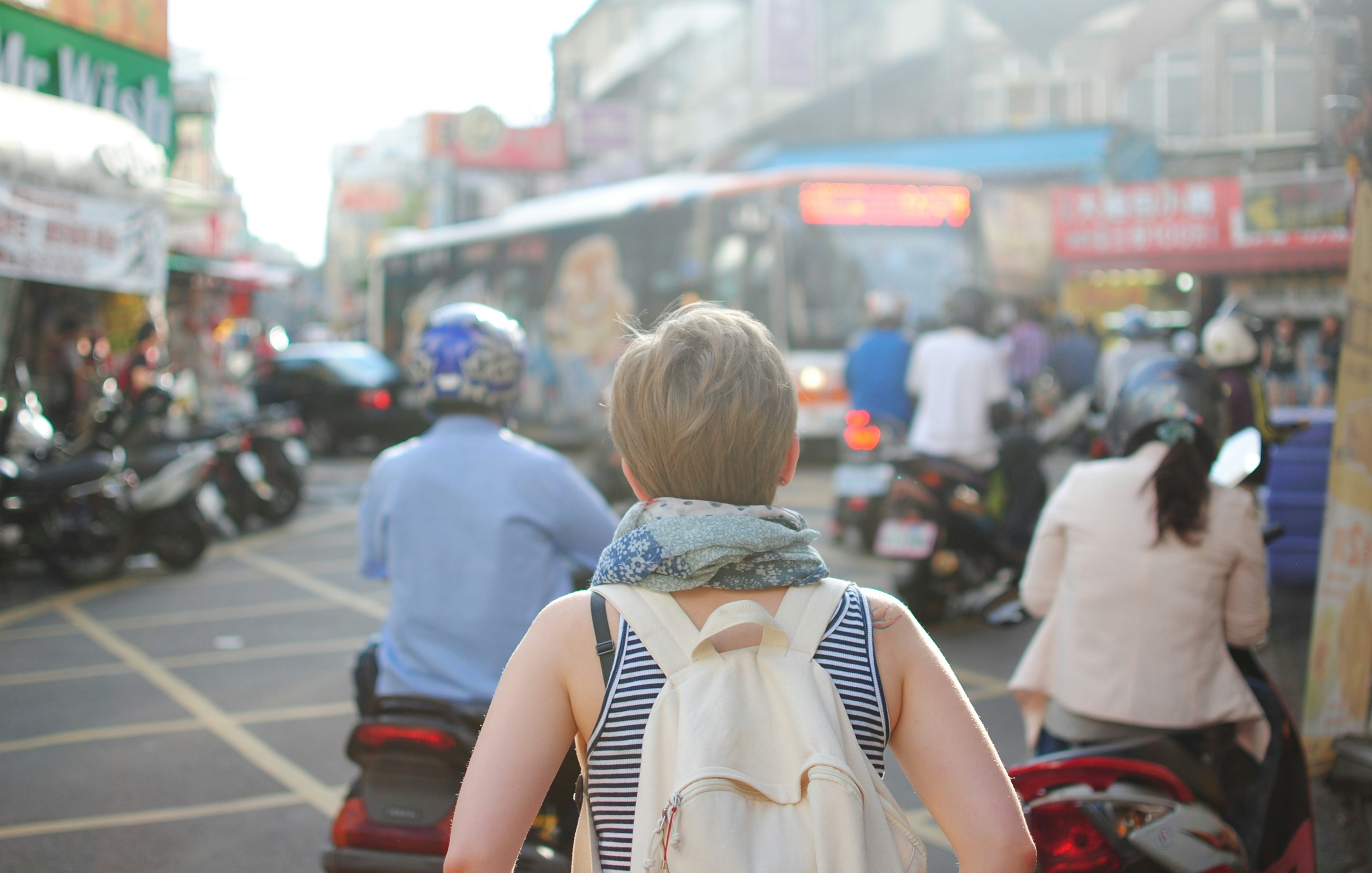 woman wearing backpack walking on road
