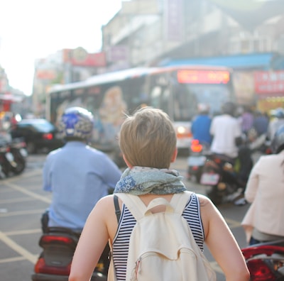 woman wearing backpack walking on road