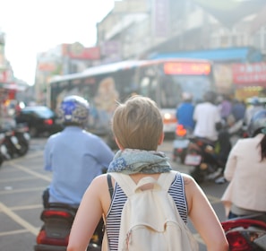 woman wearing backpack walking on road