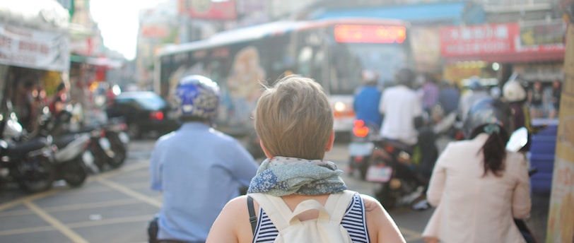 woman wearing backpack walking on road