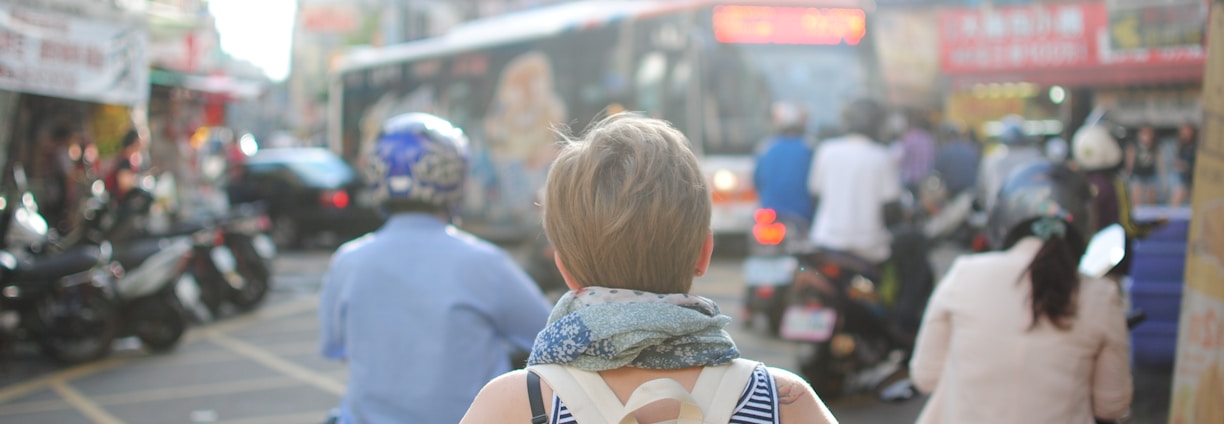 woman wearing backpack walking on road