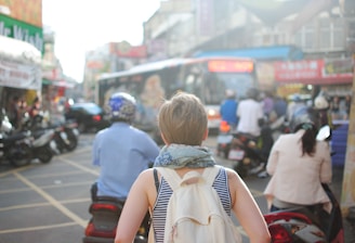 woman wearing backpack walking on road