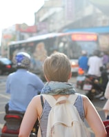 woman wearing backpack walking on road