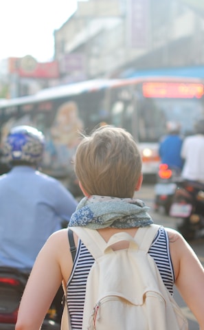 woman wearing backpack walking on road