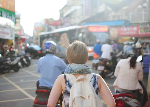 woman wearing backpack walking on road