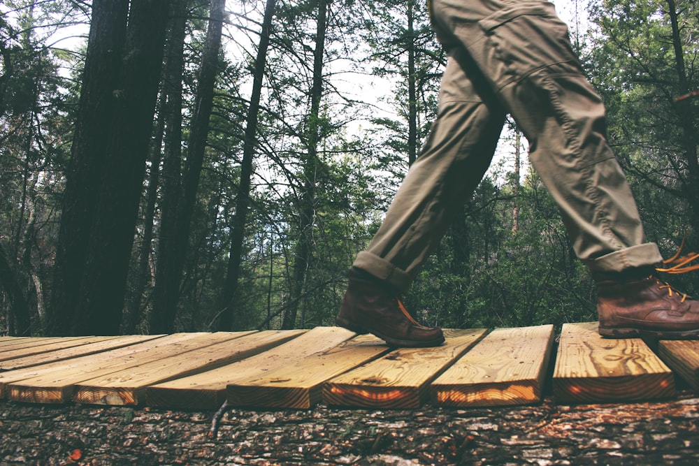 Persona che cammina sul ponte di legno marrone