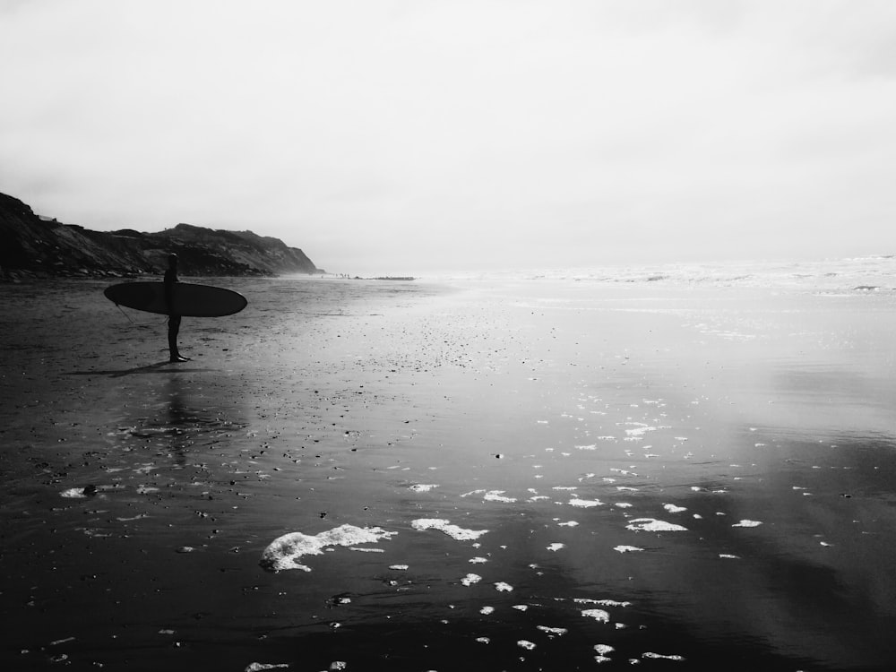 man holding skimboard near sea