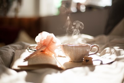 teacup on book beside pink flower decor gingerbread woman teams background