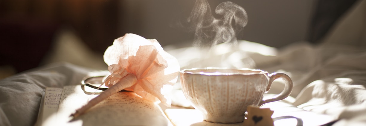 teacup on book beside pink flower decor