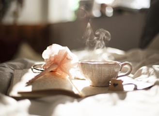 teacup on book beside pink flower decor