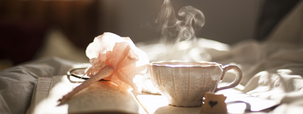 teacup on book beside pink flower decor